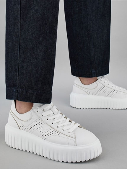 Hogan Pair of white sneakers worn by a woman in jeans