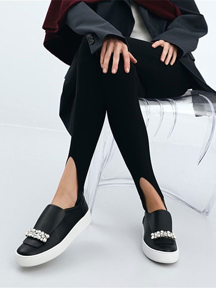 SERGIO ROSSI Pair of black shoes with stars worn by a woman sitting on a transparent chair